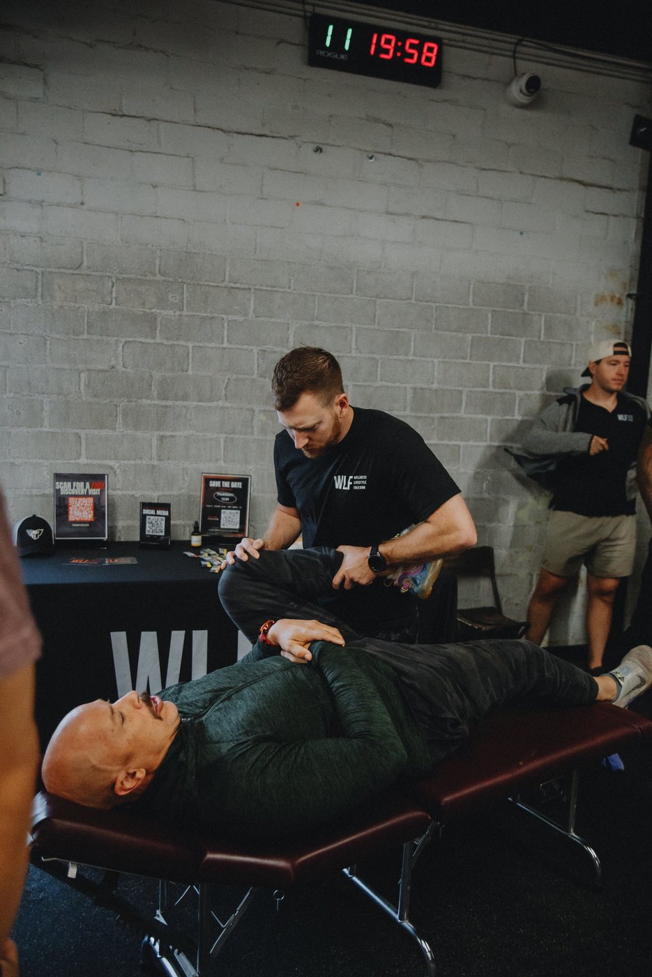 A WLF coach cueing a client through a mat rehab exercise in the turf lane.