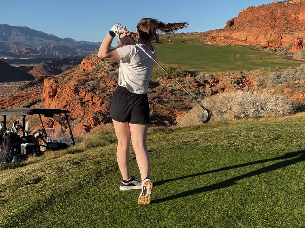 A golfer at the finish of a full swing, seen from behind, weight through onto the lead foot.