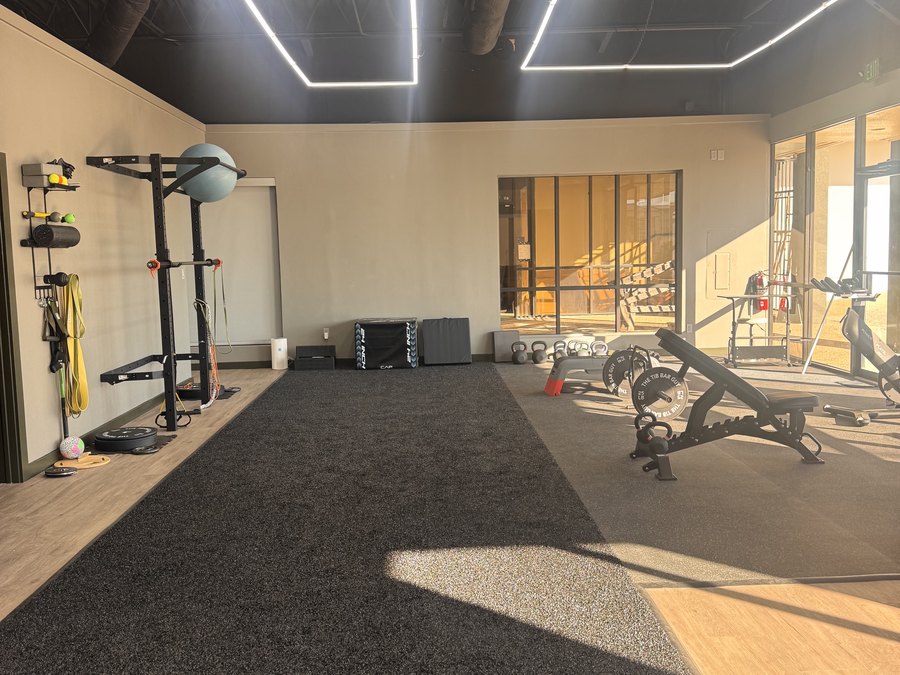 The rehab and strength floor at WLF Club, with a squat rack, kettlebells, and bands on the wall.
