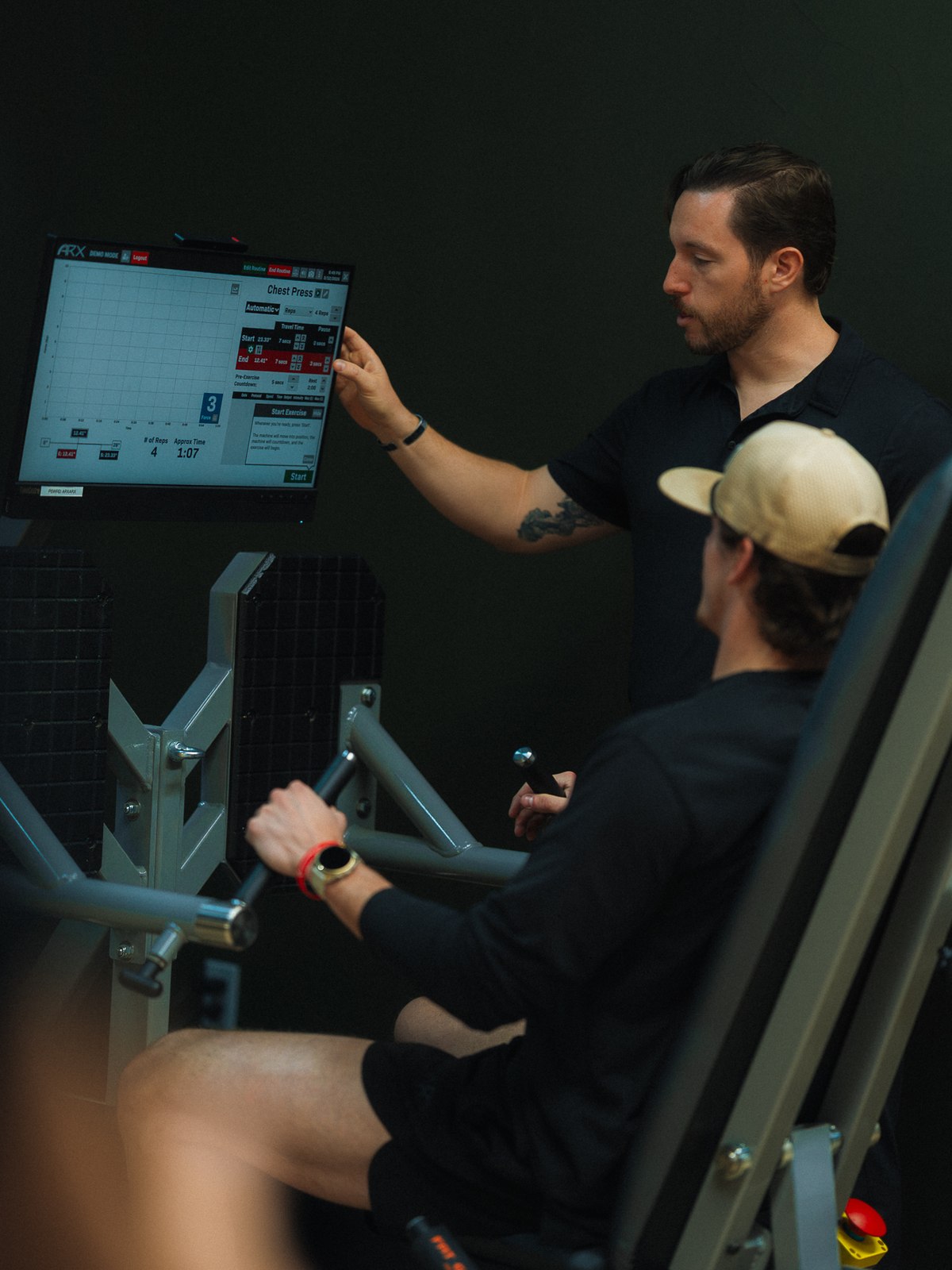 A WLF trainer reading the ARX force display while a member trains on the machine.