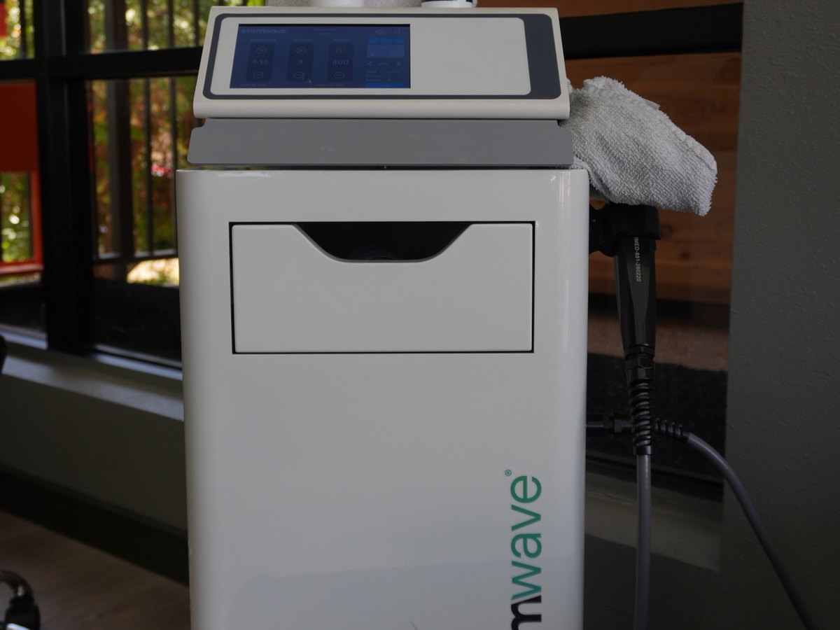 The StemWave shockwave therapy unit at WLF Club, its handpiece coiled on the side and its control screen lit.