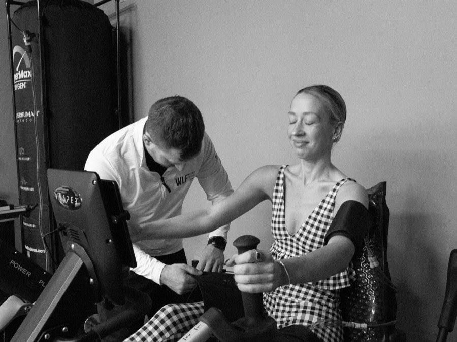 A WLF coach fitting a Vasper cuff to a seated member, in black and white.