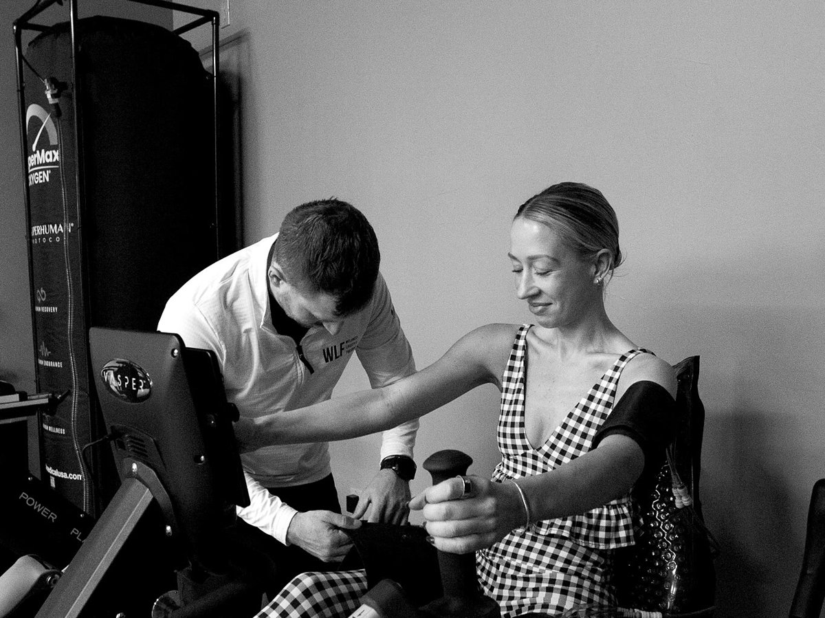 A WLF coach fitting a pneumatic Vasper cuff to a seated member.